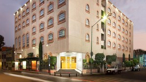 Un hotel de varios pisos con una fachada simétrica, ventanas amplias y una entrada central con escalones.