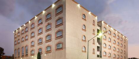 Um hotel com vários andares, fachada simétrica, janelas uniformemente distribuídas e entrada central.