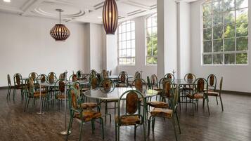 A spacious room with high ceilings, large windows, and a modern chandelier.