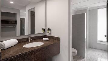 Un baño moderno con encimera de granito, un lavamanos y un espejo.