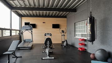 Un gimnasio con cintas de correr, elíptica, bicicleta estática, saco de boxeo y pelotas de ejercicio.