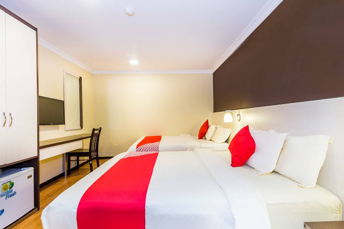 A hotel room with a large bed, a desk, and a wardrobe.