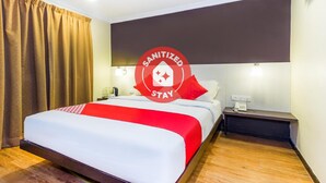 Habitación de hotel con cama, mesita de noche, escritorio, teléfono y aire acondicionado de pared.