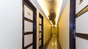 A hotel hallway with doors labeled 107 and 102, a tiled floor, and a ceiling with recessed lighting. - OYO 431 Hotel De Grand Orchard (Kuala Lumpur)