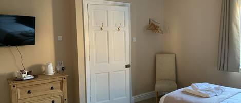 A hotel room with a bed, a chair, a dresser, a television, and a door.