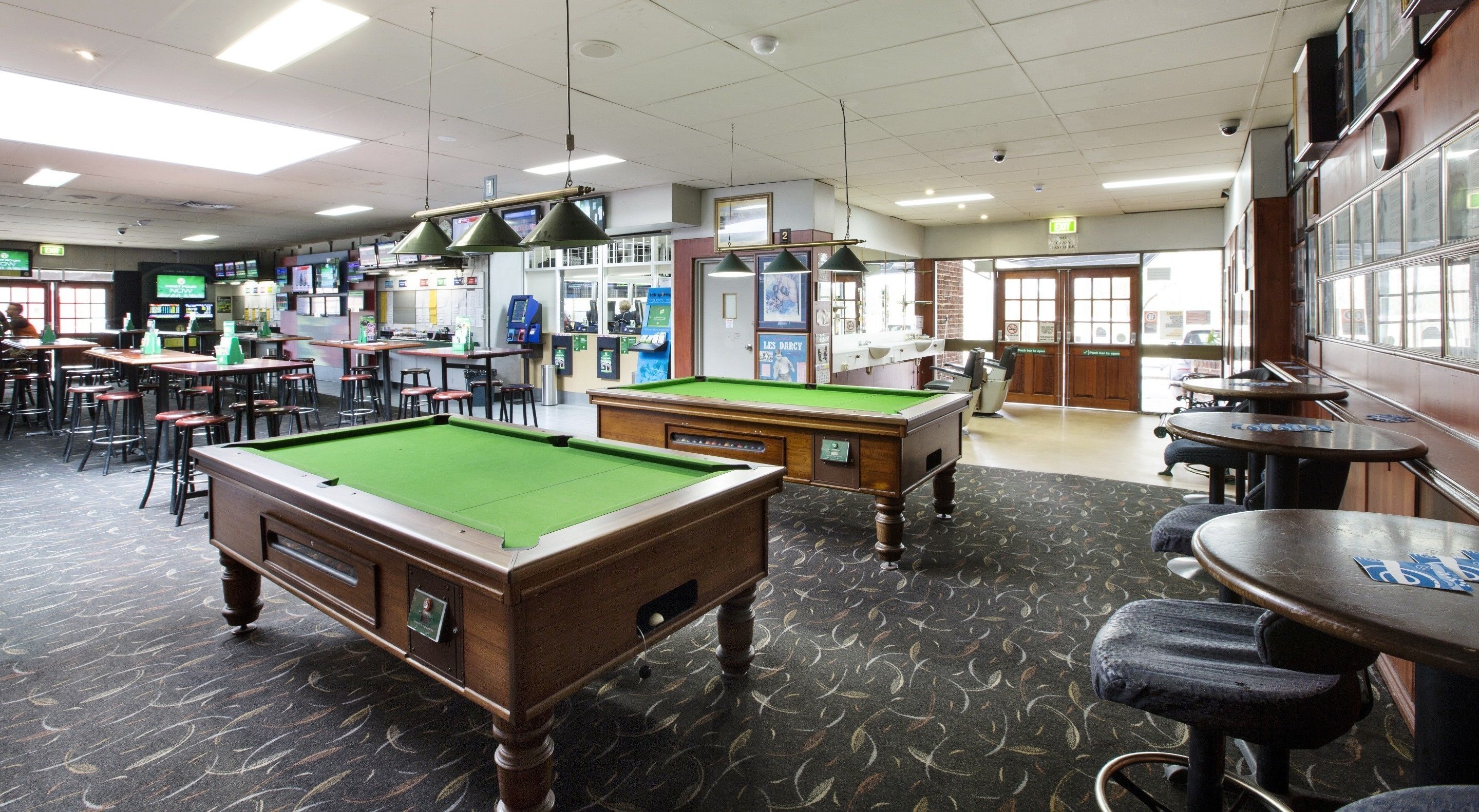 A billiards room with pool tables, bar area, and seating.