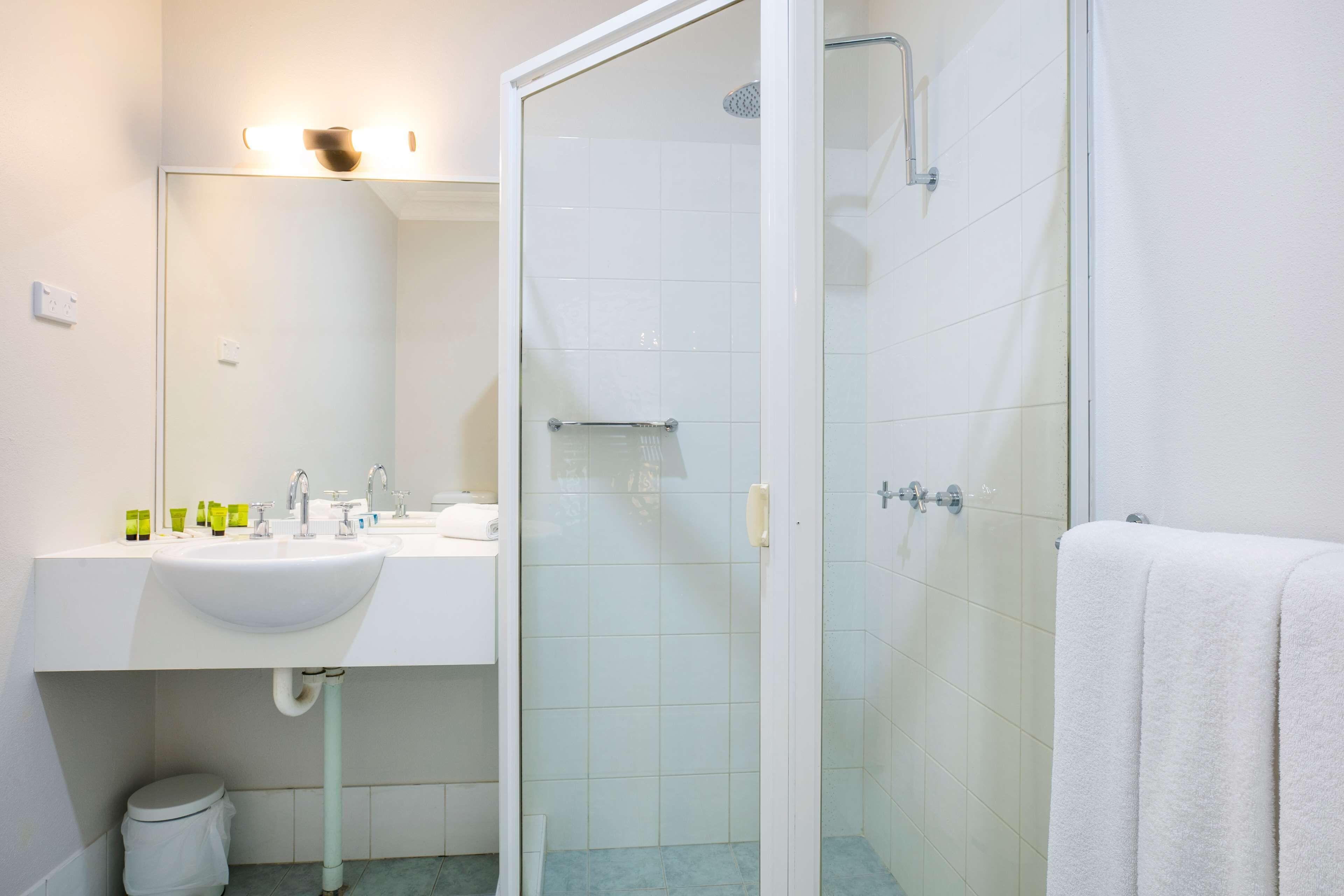 Une salle de bain avec un lavabo blanc, un miroir et une douche à parois de verre.