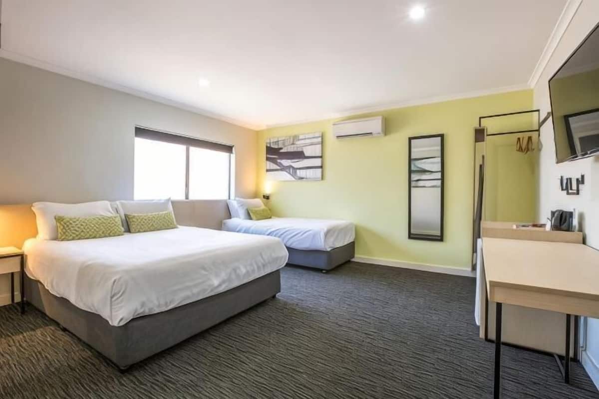 A hotel room with a large bed, a smaller bed, a desk, and a mirror.