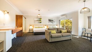A modern hotel room with a kitchenette, a sofa, a bed, and artwork on the walls. - Nightcap at Blue Cattle Dog Hotel (St Clair)