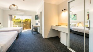 A hotel room with two beds, a desk, a large mirror, and a balcony with a view of greenery. - Nightcap at Blue Cattle Dog Hotel (St Clair)