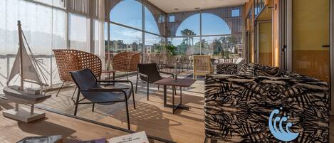 Un hall d’hôtel moderne doté de grandes fenêtres, offrant différents types de sièges et une vue sur l’extérieur.