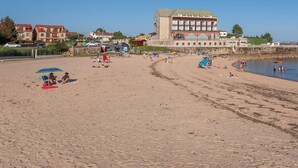A beach with a large building in the background, a sandy shore, and people engaging in various activities. - Hotel Norat Palmeira Playa (Ribeira)