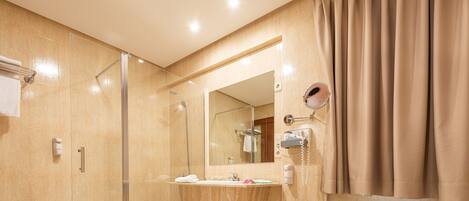 Un baño moderno con cabina de ducha de vidrio, tocador con espejo y perchero para toallas.