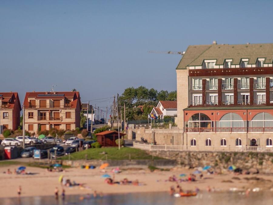 Hotel frente al mar con múltiples balcones y fachada de piedra.