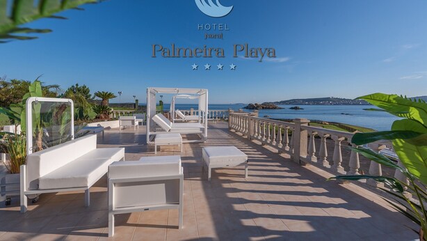 A hotel patio with white furniture, a view of the sea, and a logo for HOTEL Noral Palmaira Playa. - Hotel Norat Palmeira Playa (Ribeira)