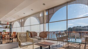 A spacious balcony with large windows, wicker furniture, and a view of the water. - Hotel Norat Palmeira Playa (Ribeira)