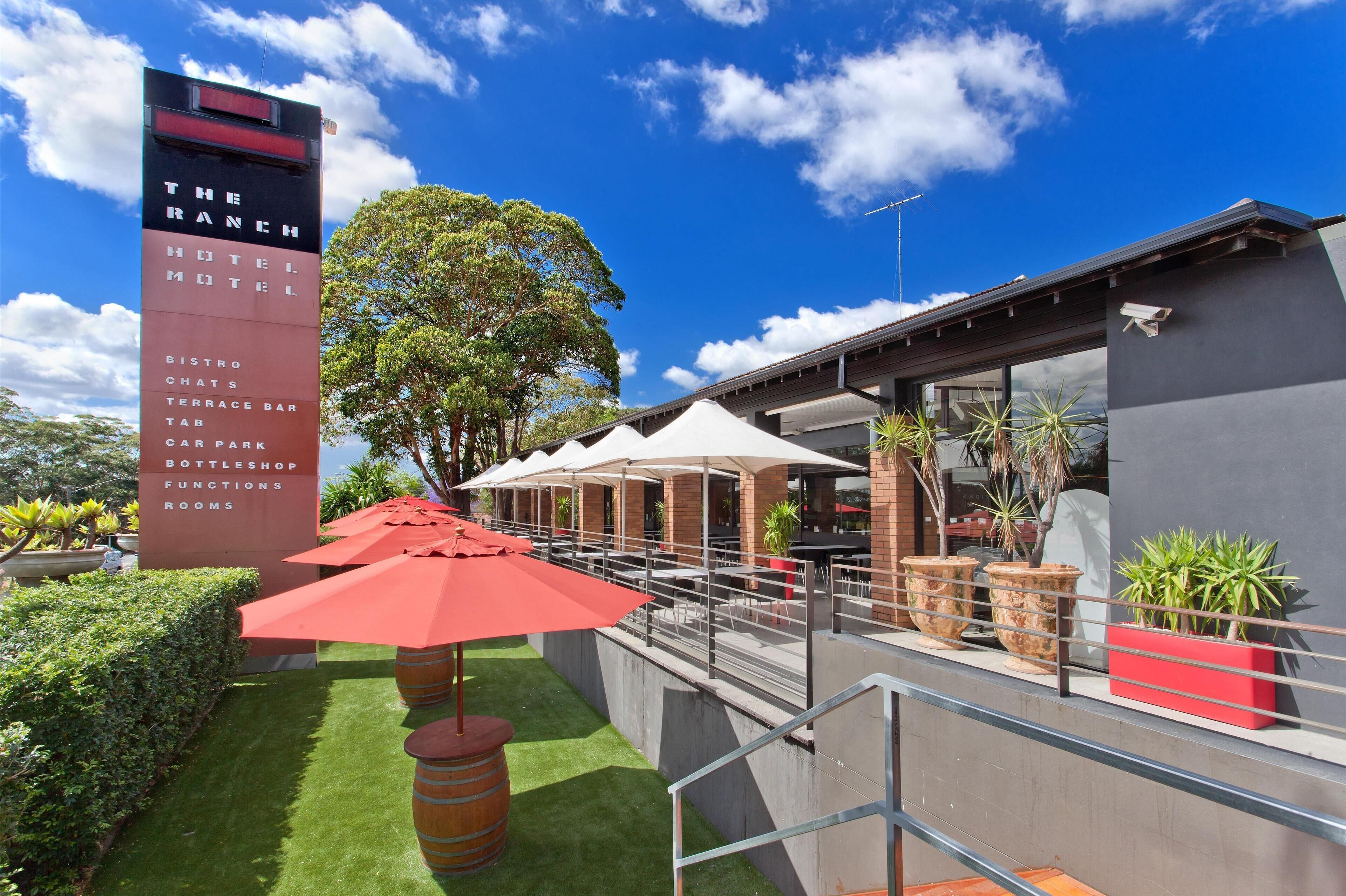 A modern hotel with a prominent sign listing amenities like a bistro, terrace bar, and car park.