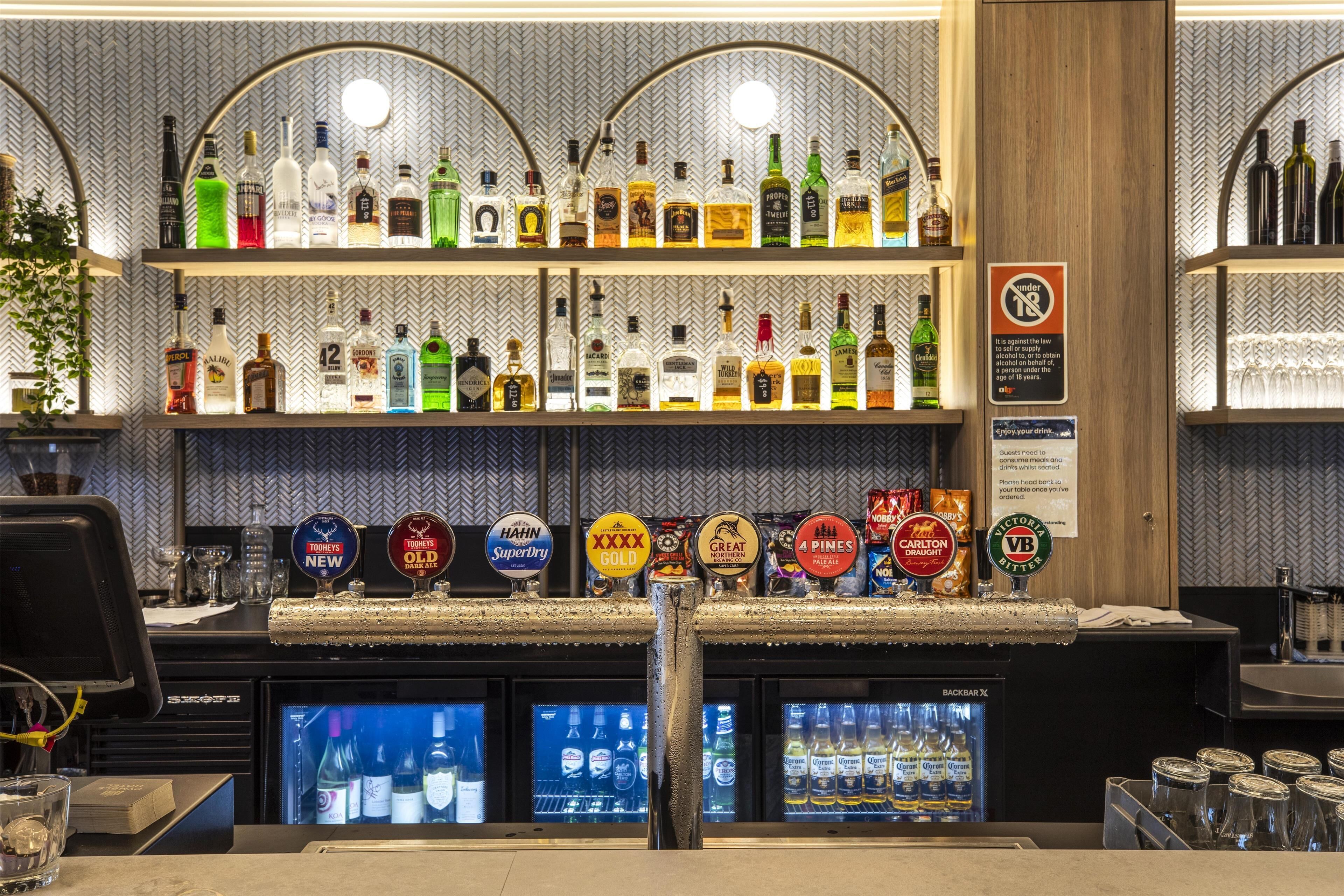 A bar area with multiple shelves of liquor bottles and a selection of beer taps.