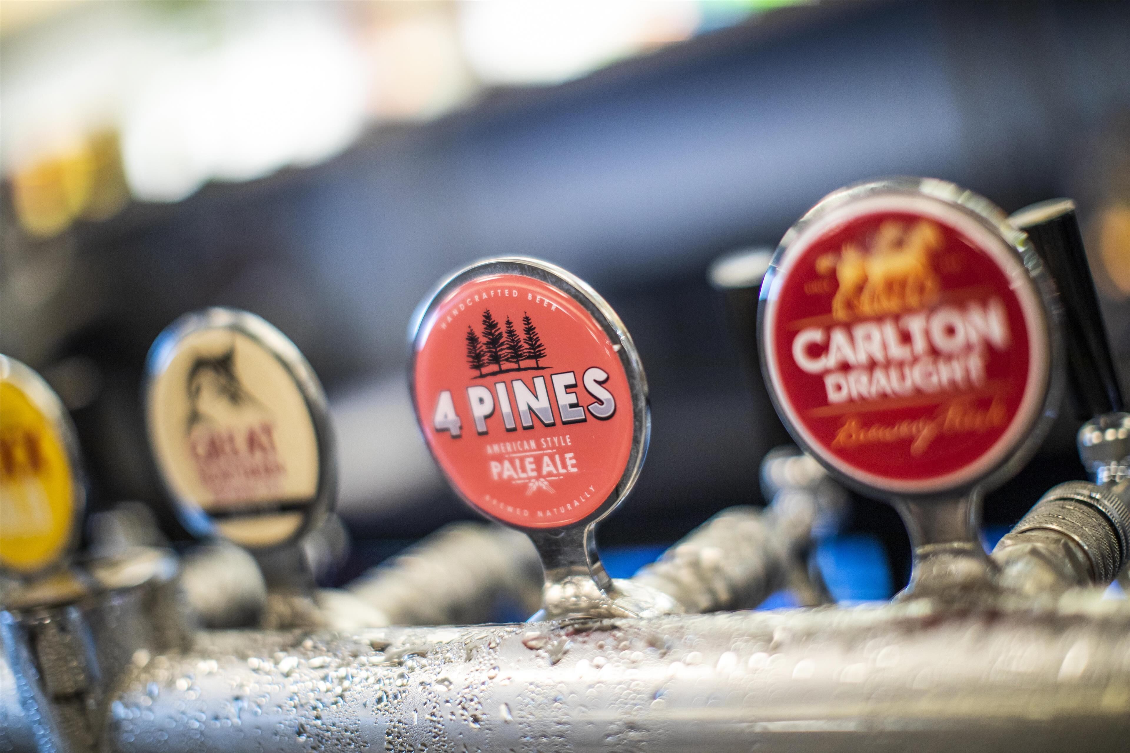 En bar med haner mærket '4 Pines Pale Ale' og 'Carlton Draught'.