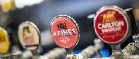 En bar med haner mærket '4 Pines Pale Ale' og 'Carlton Draught'.