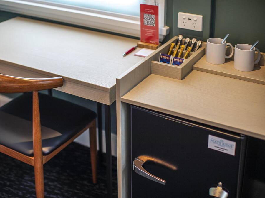 A desk with a chair, a coffee station, and a filing cabinet.