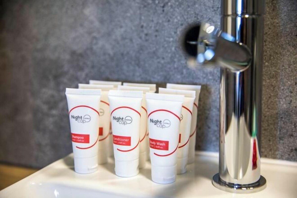 A row of white tubes with red labels labeled "Night Cap" on a white surface next to a chrome faucet.