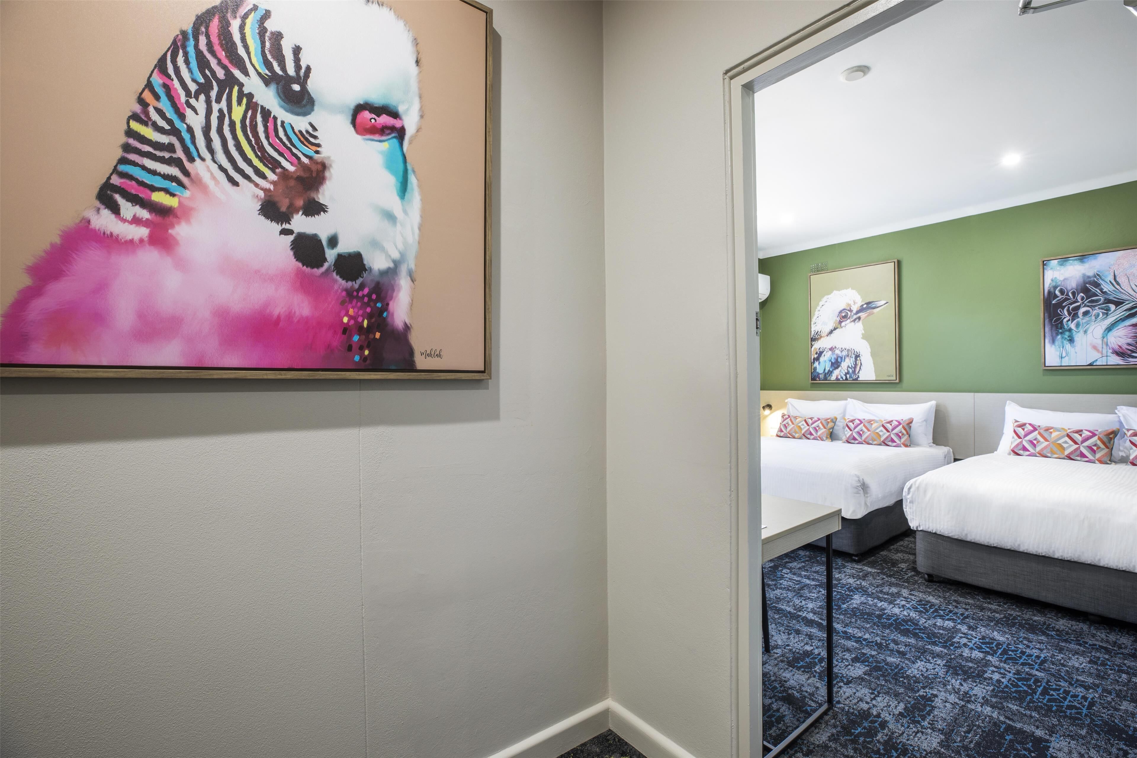 A hotel room with two beds, a green wall, and a zebra painting.