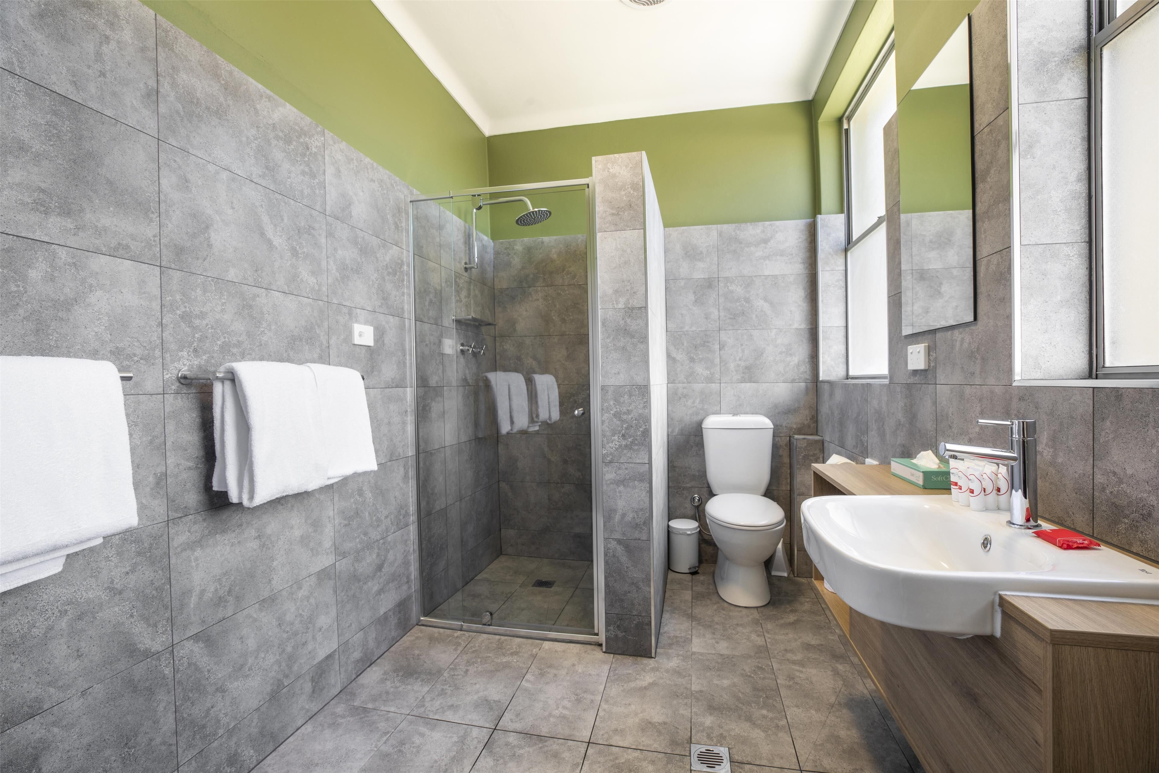 A modern bathroom with a glass-enclosed shower, a white toilet, and a freestanding bathtub.