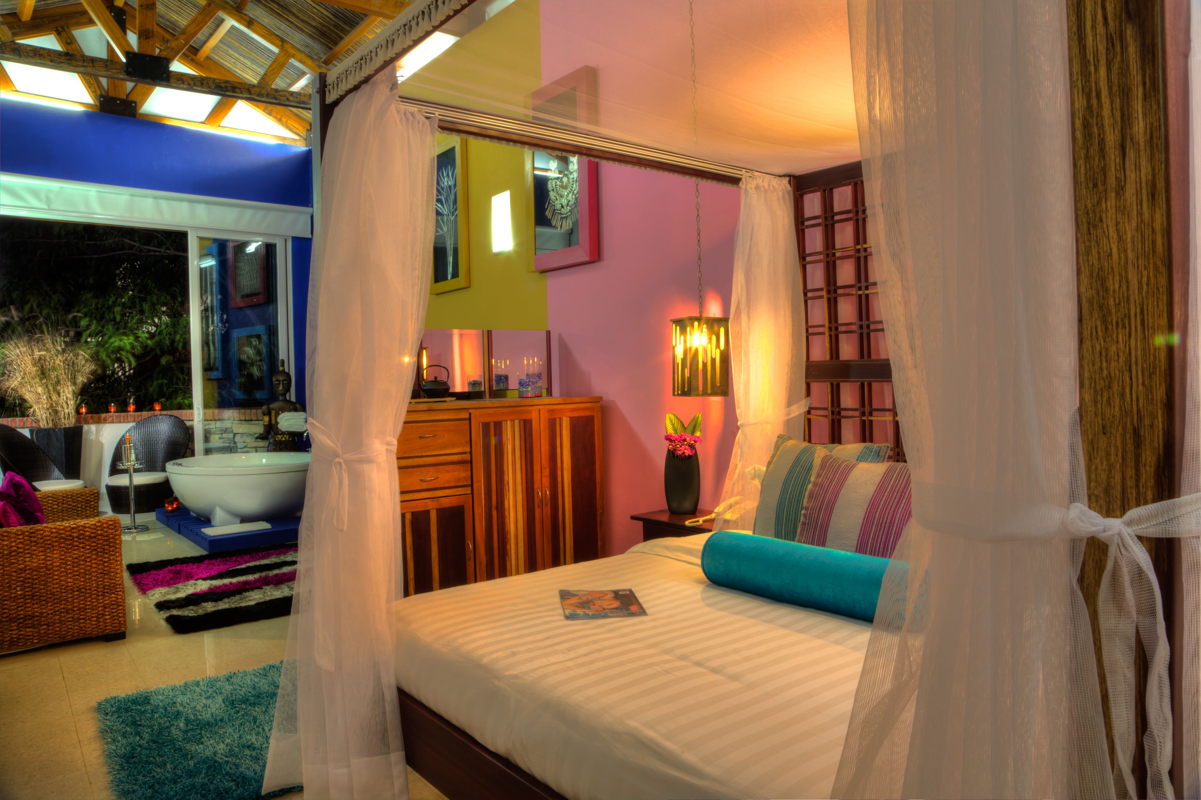 A bedroom with a bed, a nightstand, a window, and a bathroom visible through the glass door.