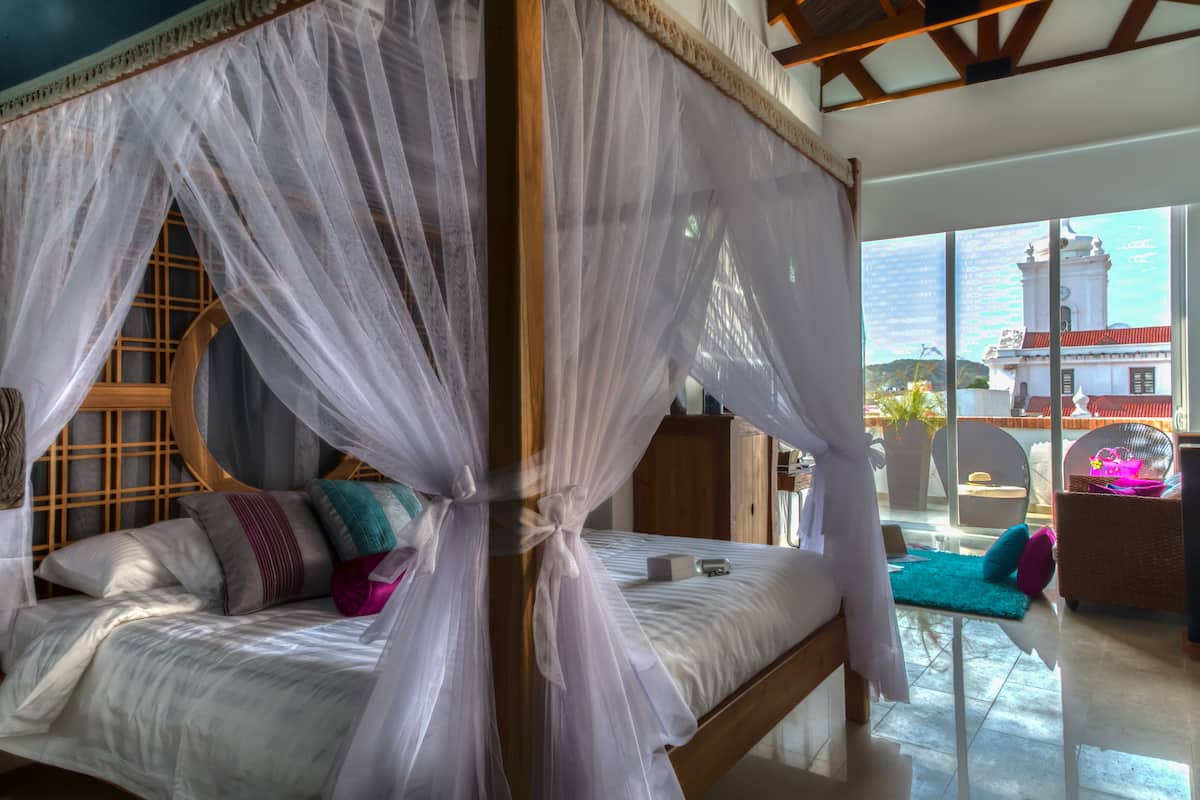 A four-poster bed with a canopy, a wooden headboard, and multiple pillows.