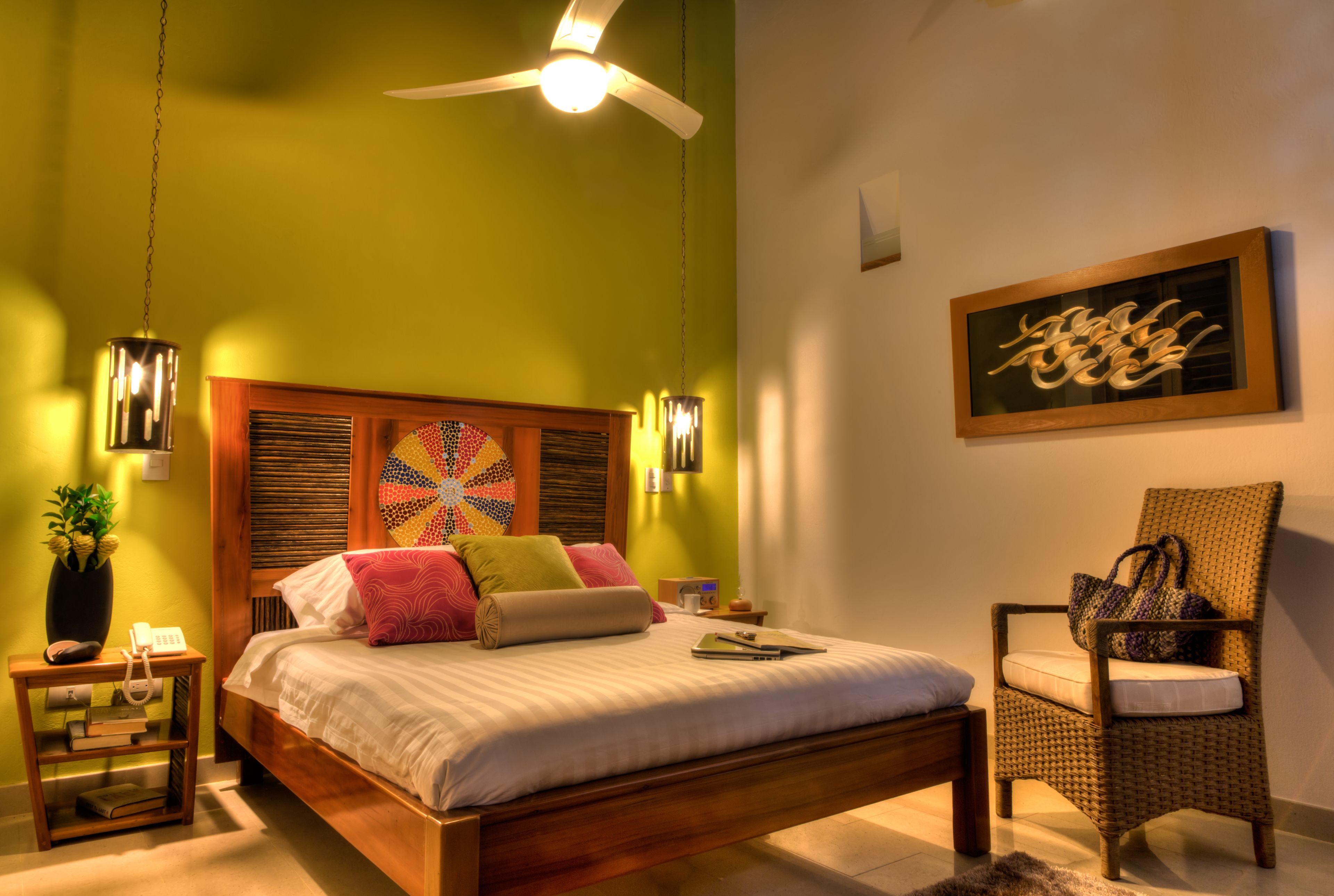 A bedroom with a wooden bed, a chair, a wall art piece, and a ceiling fan.
