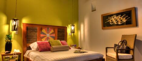 A bedroom with a wooden bed, a chair, a wall art piece, and a ceiling fan.