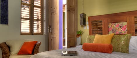 A bedroom with a bed, a wicker chair, and a wooden headboard.