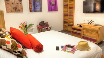 Habitación de hotel ordenada con cama, escritorio, televisor y armario.
