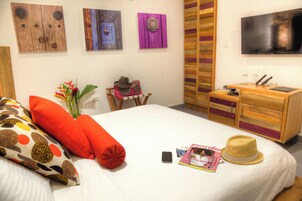 Habitación de hotel ordenada con cama, escritorio, televisor y armario.