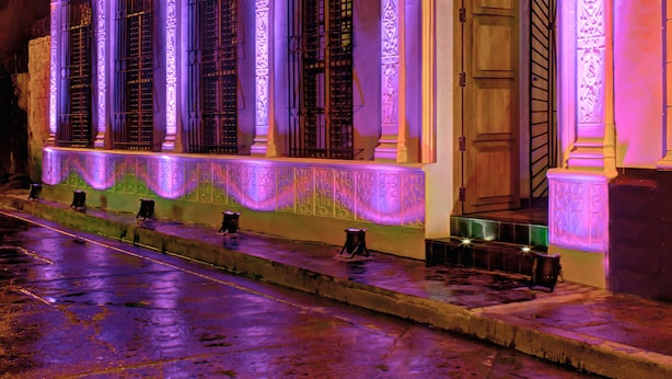 A building with ornate columns and decorative moldings, illuminated by purple lighting. - Casa de Leda, a Kali Hotel (Santa Marta)