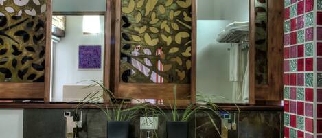 A bathroom with a wooden vanity, two large mirrors, and a decorative panel with leaf patterns.