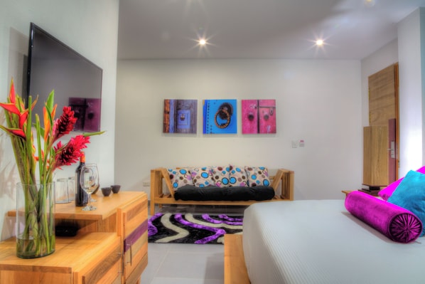 A modern bedroom with a bed, a wooden dresser, a TV, and artwork on the wall. - Casa de Leda, a Kali Hotel (Santa Marta)
