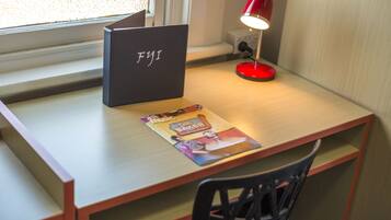 A desk with a laptop, a red desk lamp, and a magazine.