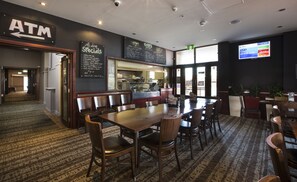 A restaurant interior with a wooden dining area, an ATM, and a chalkboard menu. - Melton Hotel (Auburn)