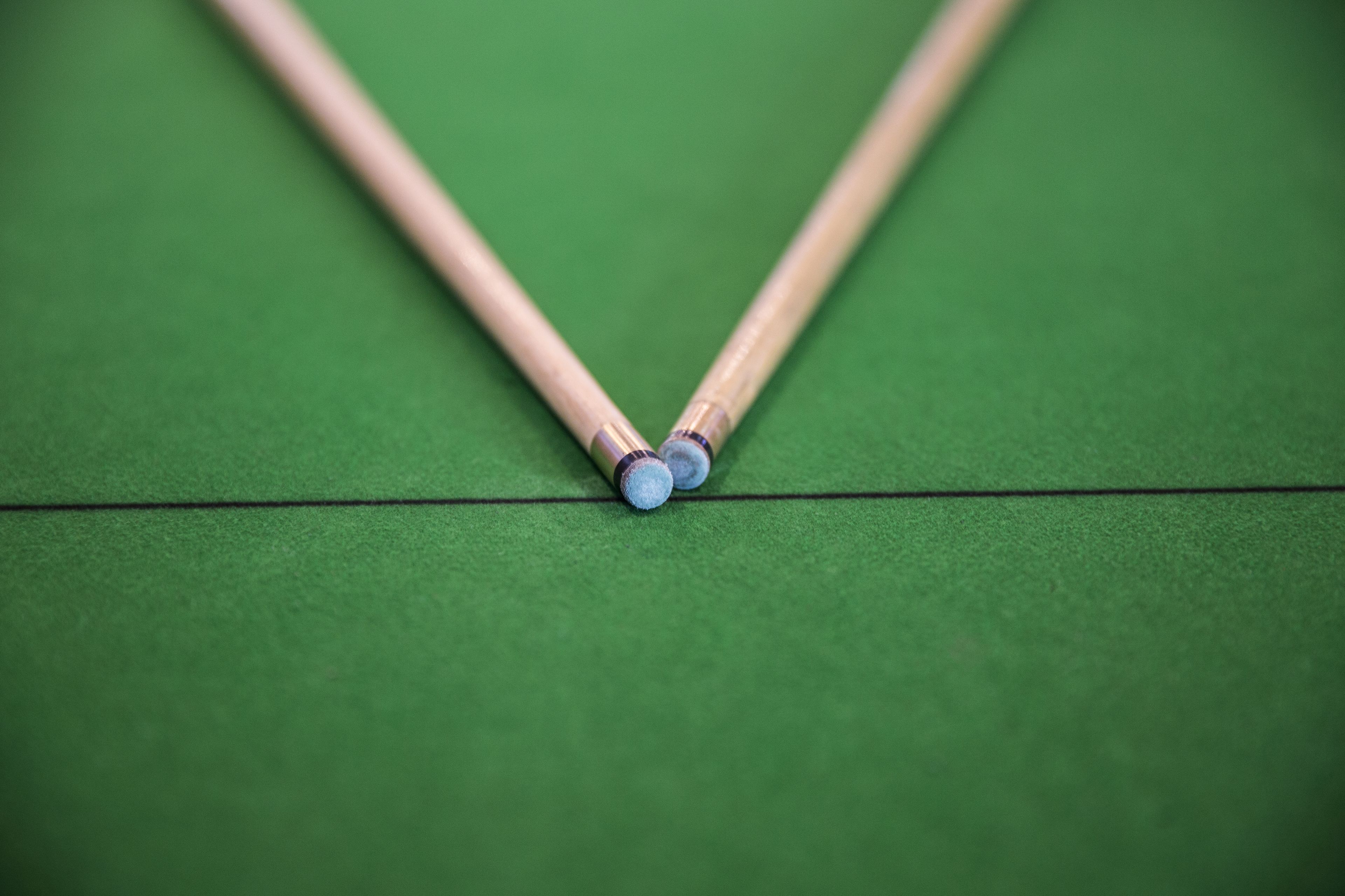 Two pool cues on a green felt surface.