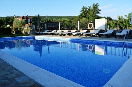 Una piscina al aire libre, sillones reclinables de piscina
