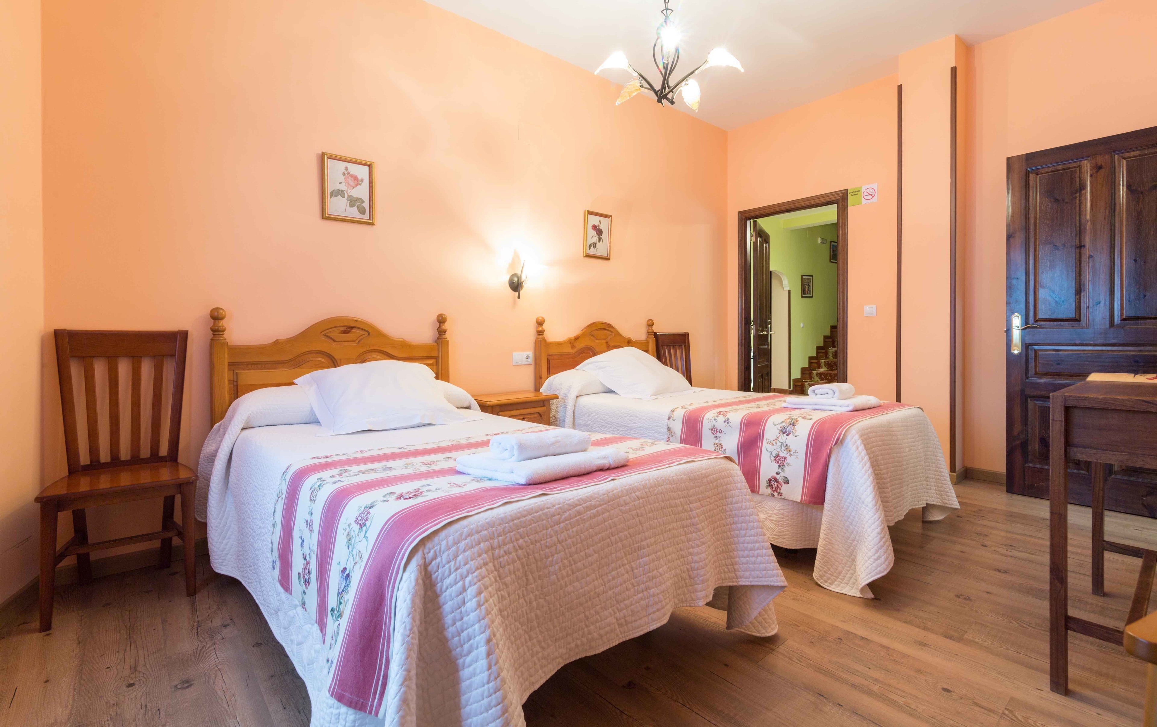 Quarto com duas camas, cabeceiras de madeira e uma cadeira de madeira.