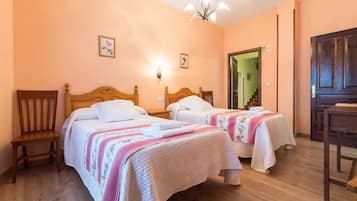 Quarto com duas camas, cabeceiras de madeira e uma cadeira de madeira.