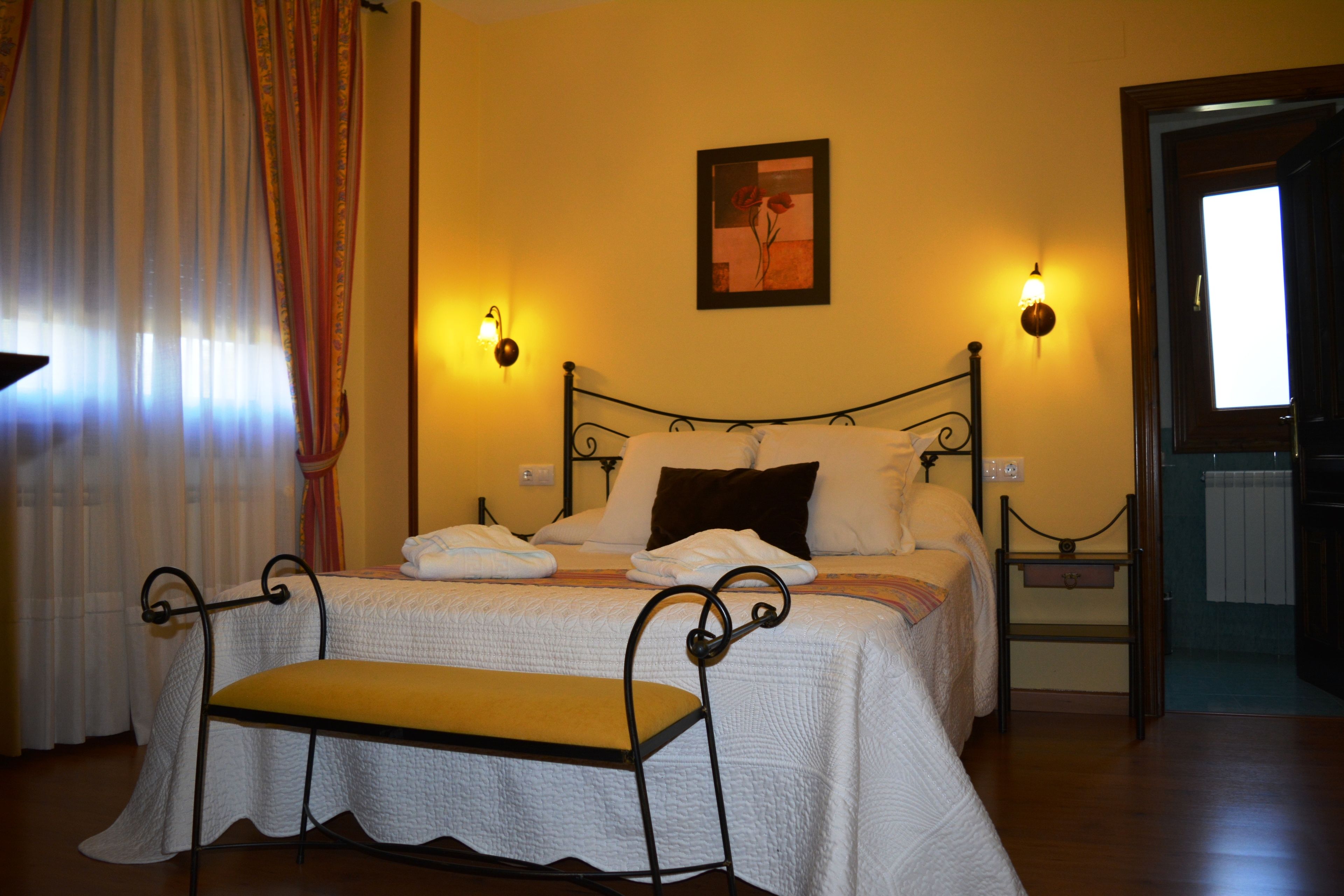 A neatly arranged bedroom with a bed, bedside lamps, and a bench.
