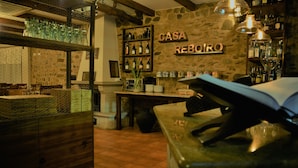 Un coin bar accueillant, avec un mur en pierre, des étagères remplies de bouteilles et un comptoir en bois.