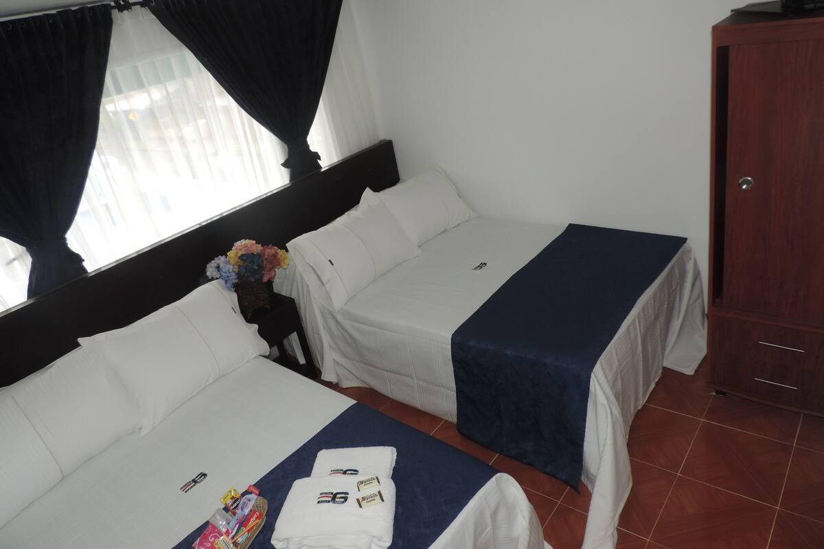 Une chambre d’hôtel avec deux lits, une télévision et une armoire.