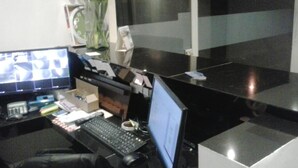 Ein modernes Büro mit Schreibtisch, Computer und Blumen in einer Vase.