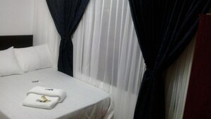 Ein Hotelzimmer mit einem ordentlich bezogenen Bett, weißer Bettwäsche und einem Paar Handtüchern auf dem Bett.