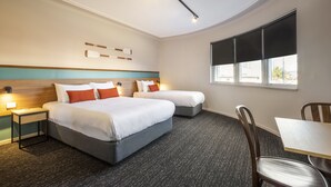 Habitación de hotel con dos camas, un escritorio y una silla.
